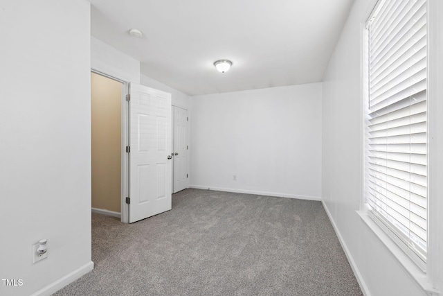 carpeted empty room featuring baseboards