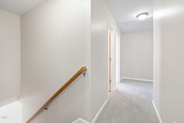 corridor with attic access, carpet, baseboards, and an upstairs landing