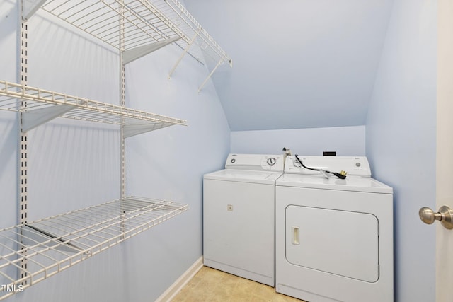 washroom featuring laundry area, baseboards, and washer and clothes dryer