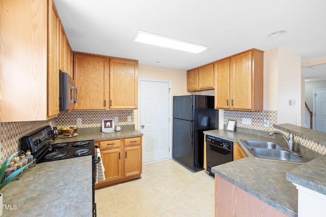 kitchen with light floors, backsplash, a sink, a peninsula, and black appliances