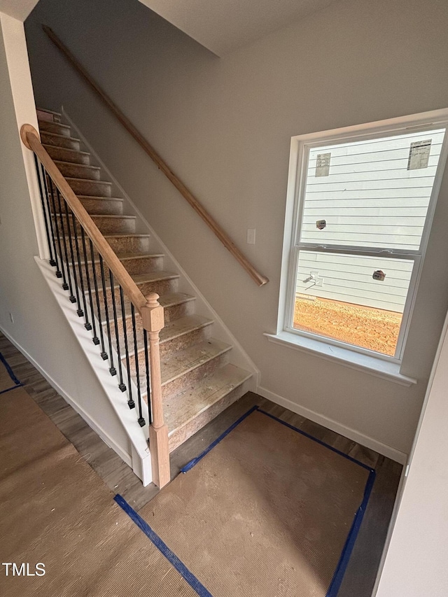 staircase with baseboards and wood finished floors