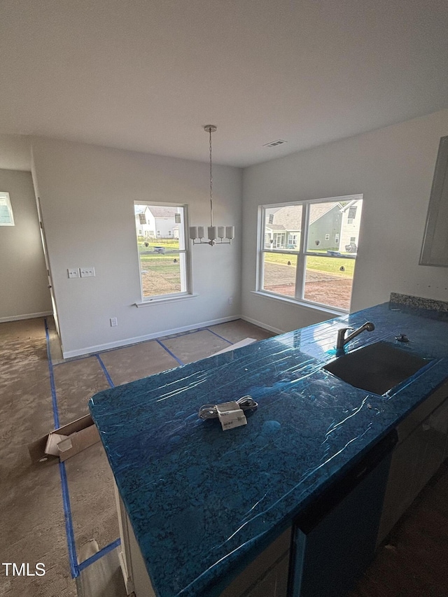 kitchen with a sink, dishwashing machine, and baseboards