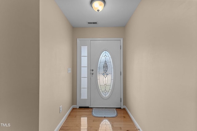 foyer entrance featuring visible vents, light wood-style flooring, and baseboards