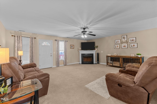 living area featuring visible vents, baseboards, carpet floors, a fireplace with flush hearth, and ceiling fan