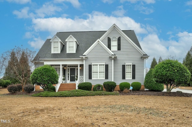 cape cod-style house with a shingled roof and a front lawn