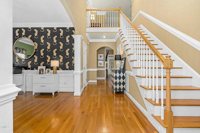 foyer entrance with ornate columns, baseboards, crown molding, and wood finished floors