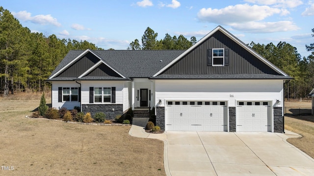 craftsman house with roof with shingles, an attached garage, board and batten siding, stone siding, and driveway