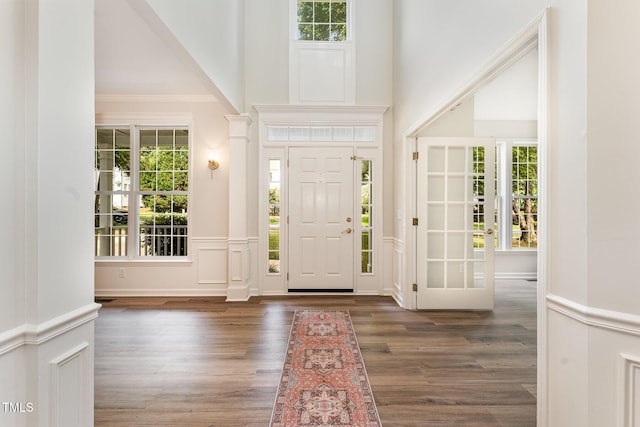 entrance foyer with wainscoting, plenty of natural light, wood finished floors, and a decorative wall