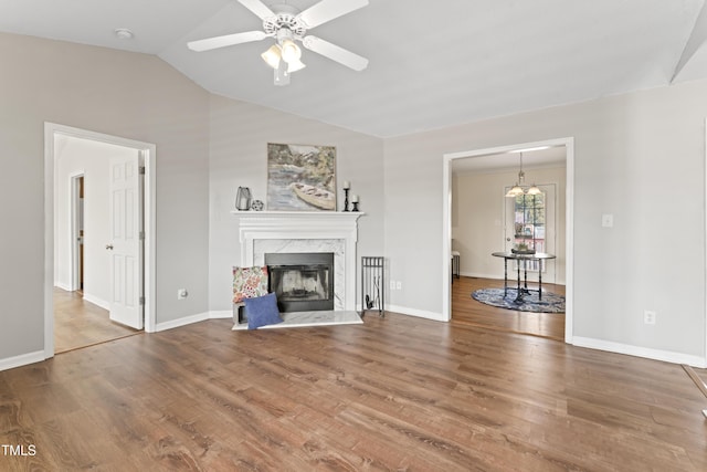 unfurnished living room with a ceiling fan, wood finished floors, vaulted ceiling, and a premium fireplace