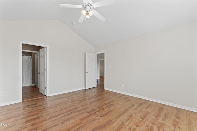 empty room with a ceiling fan, high vaulted ceiling, light wood-style flooring, and baseboards