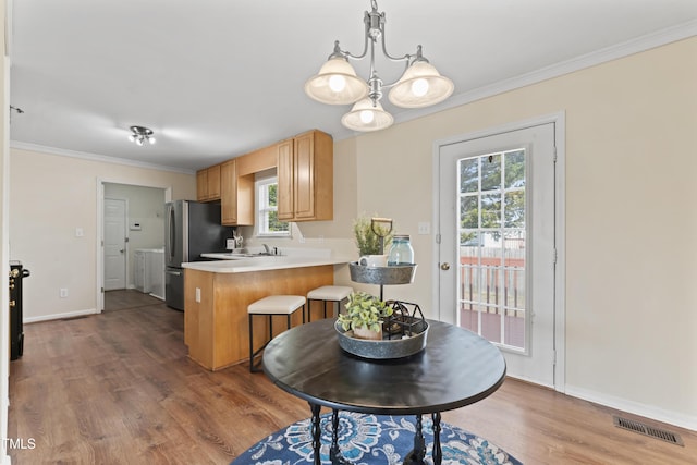 kitchen featuring ornamental molding, visible vents, a peninsula, and wood finished floors