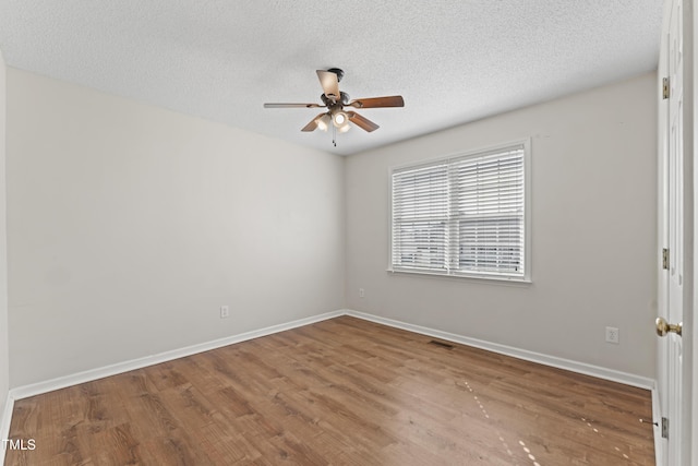 empty room featuring a textured ceiling, wood finished floors, and baseboards