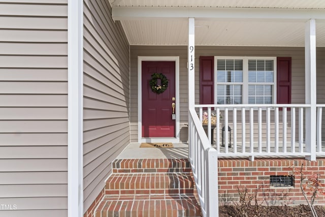 view of exterior entry featuring covered porch and brick siding