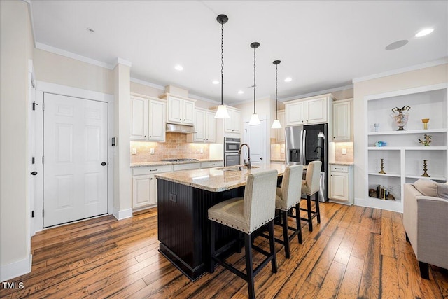 kitchen featuring appliances with stainless steel finishes, wood-type flooring, crown molding, and under cabinet range hood