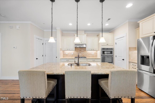 kitchen with visible vents, appliances with stainless steel finishes, a sink, wood finished floors, and under cabinet range hood