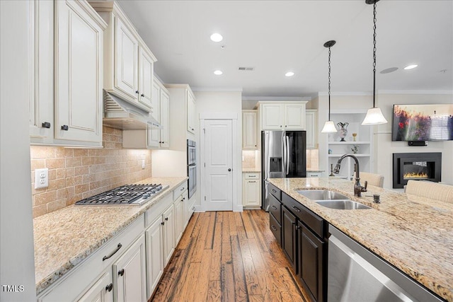 kitchen featuring under cabinet range hood, stainless steel appliances, a sink, visible vents, and hardwood / wood-style floors