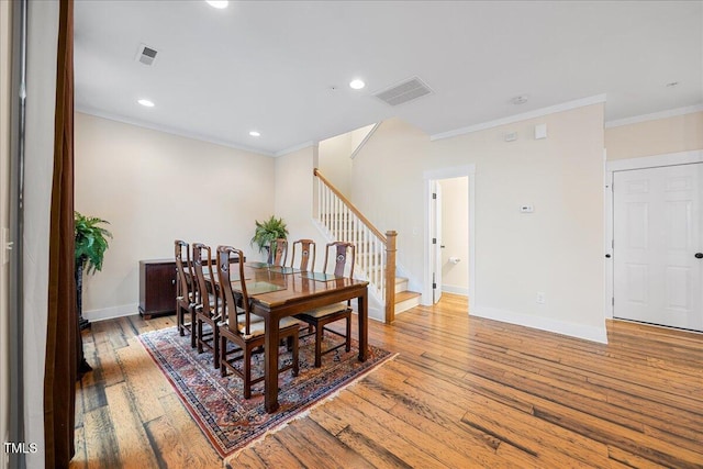 dining area with visible vents, light wood-style flooring, stairway, ornamental molding, and baseboards