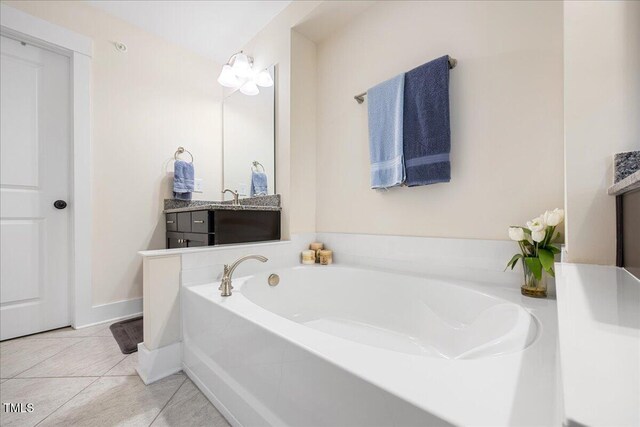 bathroom with tile patterned flooring, baseboards, a bath, and vanity