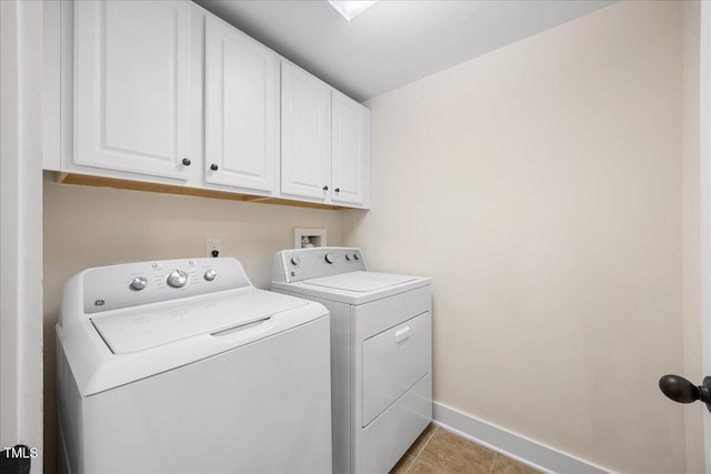 laundry area with light tile patterned floors, washing machine and dryer, cabinet space, and baseboards