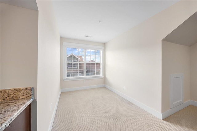 interior space with baseboards, visible vents, and light colored carpet