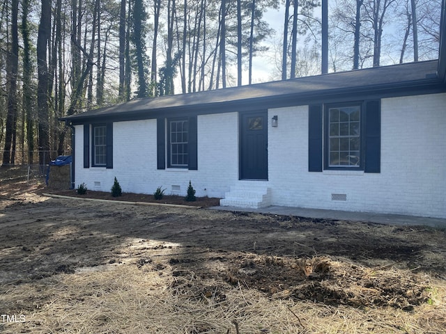 view of front of property featuring entry steps, brick siding, and crawl space