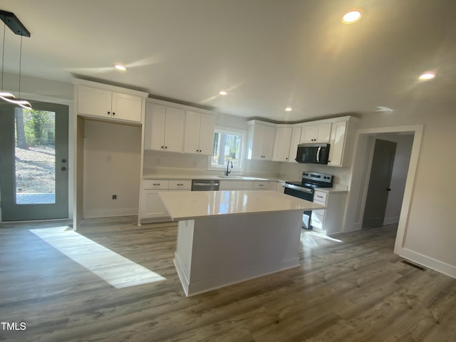 kitchen with white cabinetry, stainless steel appliances, light countertops, and pendant lighting