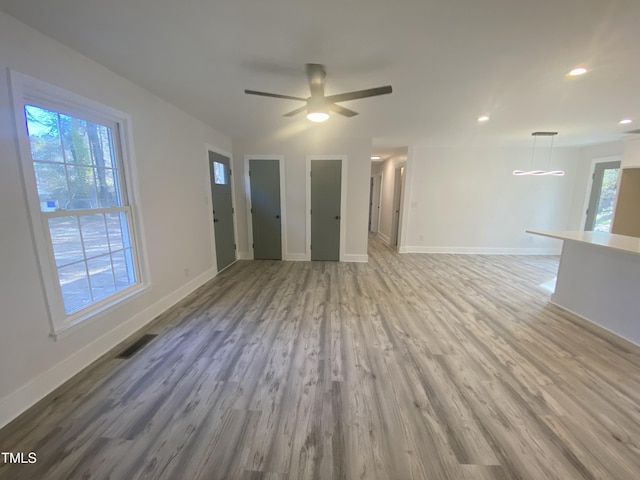 unfurnished living room with a healthy amount of sunlight, light wood-style flooring, visible vents, and baseboards