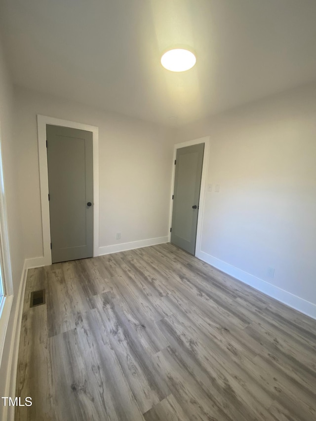 empty room with light wood-type flooring, baseboards, and visible vents