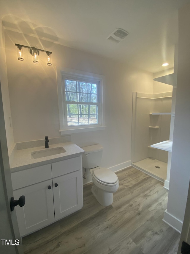 bathroom featuring visible vents, toilet, wood finished floors, walk in shower, and vanity