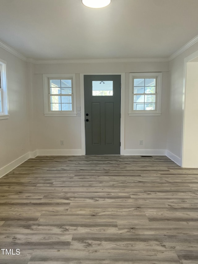 entrance foyer featuring light wood finished floors, plenty of natural light, and ornamental molding