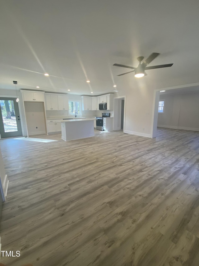 unfurnished living room with a ceiling fan, recessed lighting, and light wood-style flooring