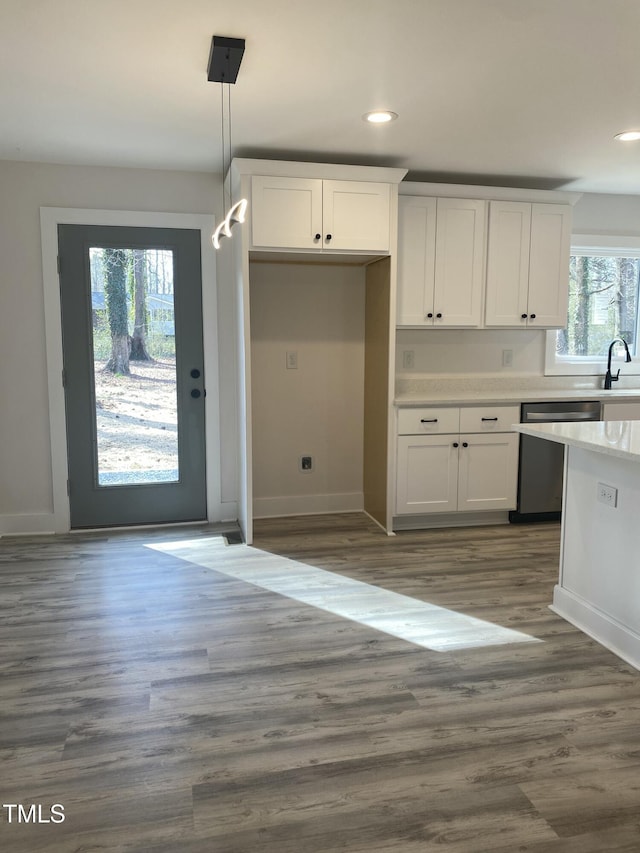 kitchen with light countertops, hanging light fixtures, white cabinetry, a sink, and dishwasher