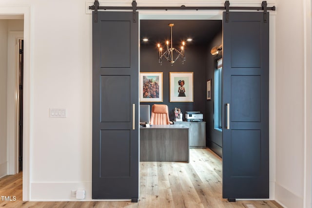 kitchen featuring hanging light fixtures, a barn door, and light wood-type flooring