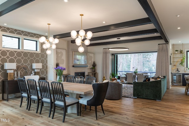 dining area featuring beam ceiling, wood finished floors, wine cooler, wallpapered walls, and an accent wall