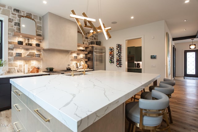 kitchen featuring a large island, light wood-style flooring, backsplash, appliances with stainless steel finishes, and light stone countertops