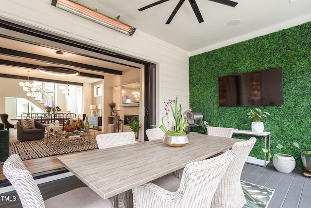 dining area with ceiling fan with notable chandelier, an accent wall, wood finished floors, a fireplace, and stairs