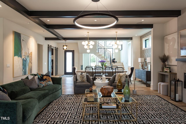 living room featuring beam ceiling, a notable chandelier, a barn door, and wood finished floors