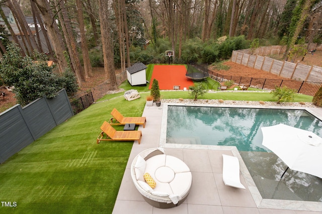 view of pool featuring a fenced in pool, a trampoline, a lawn, a fenced backyard, and an outbuilding