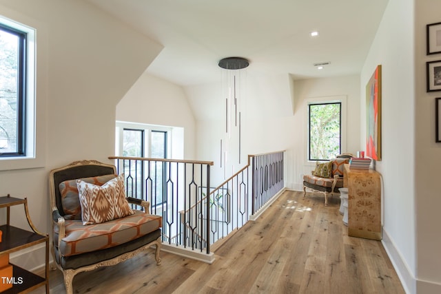 hall with hardwood / wood-style flooring, an upstairs landing, baseboards, and visible vents