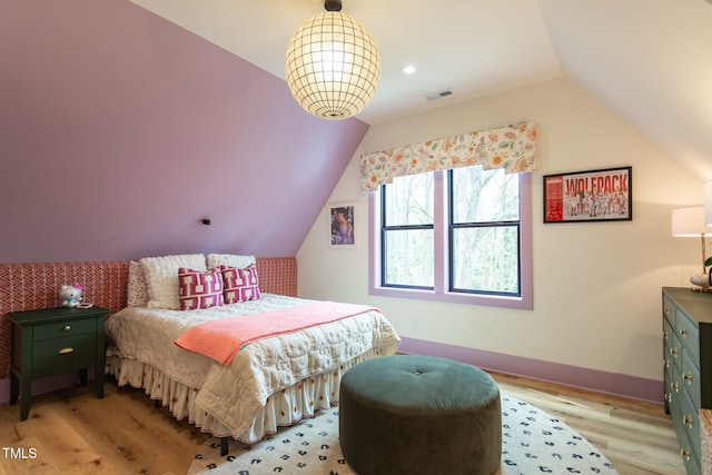 bedroom with visible vents, lofted ceiling, baseboards, and light wood finished floors