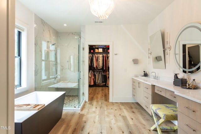 bathroom featuring a wealth of natural light, wood finished floors, visible vents, and a marble finish shower