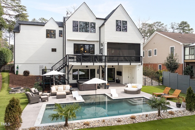 back of house featuring a hot tub, an outdoor living space with a fire pit, a sunroom, stairs, and a patio area