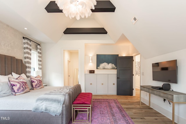 bedroom featuring lofted ceiling, wood finished floors, visible vents, and a chandelier