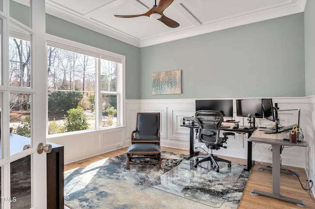 office space featuring a wainscoted wall, crown molding, a decorative wall, ceiling fan, and wood finished floors