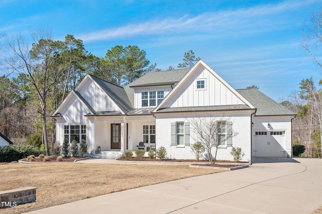 modern inspired farmhouse with a porch, an attached garage, brick siding, concrete driveway, and board and batten siding