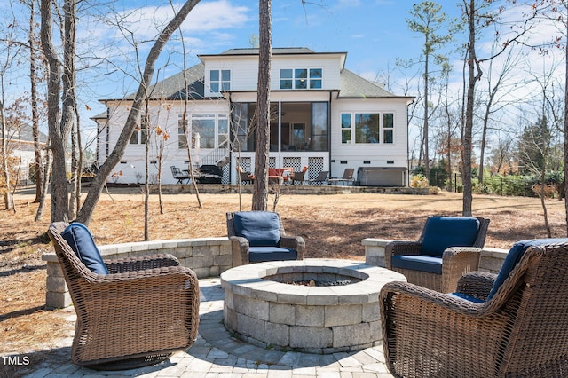 rear view of house featuring a patio, an outdoor fire pit, roof with shingles, and a sunroom