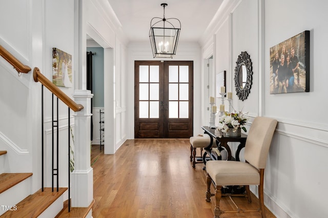 entryway featuring light wood finished floors, stairway, a chandelier, and french doors