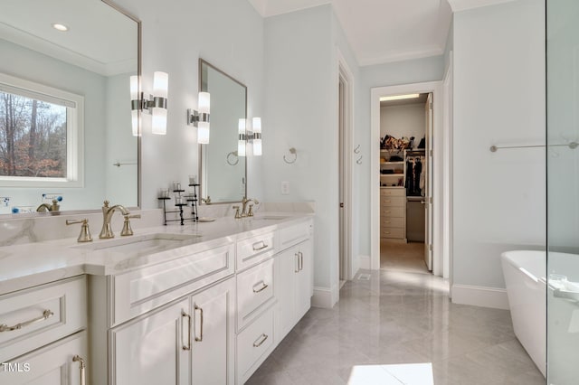 full bath featuring a walk in closet, a freestanding tub, a sink, and double vanity