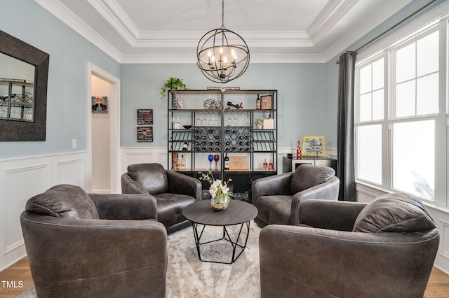 living room featuring a wainscoted wall, wood finished floors, and a raised ceiling