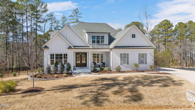 modern farmhouse style home with board and batten siding, a standing seam roof, roof with shingles, and metal roof